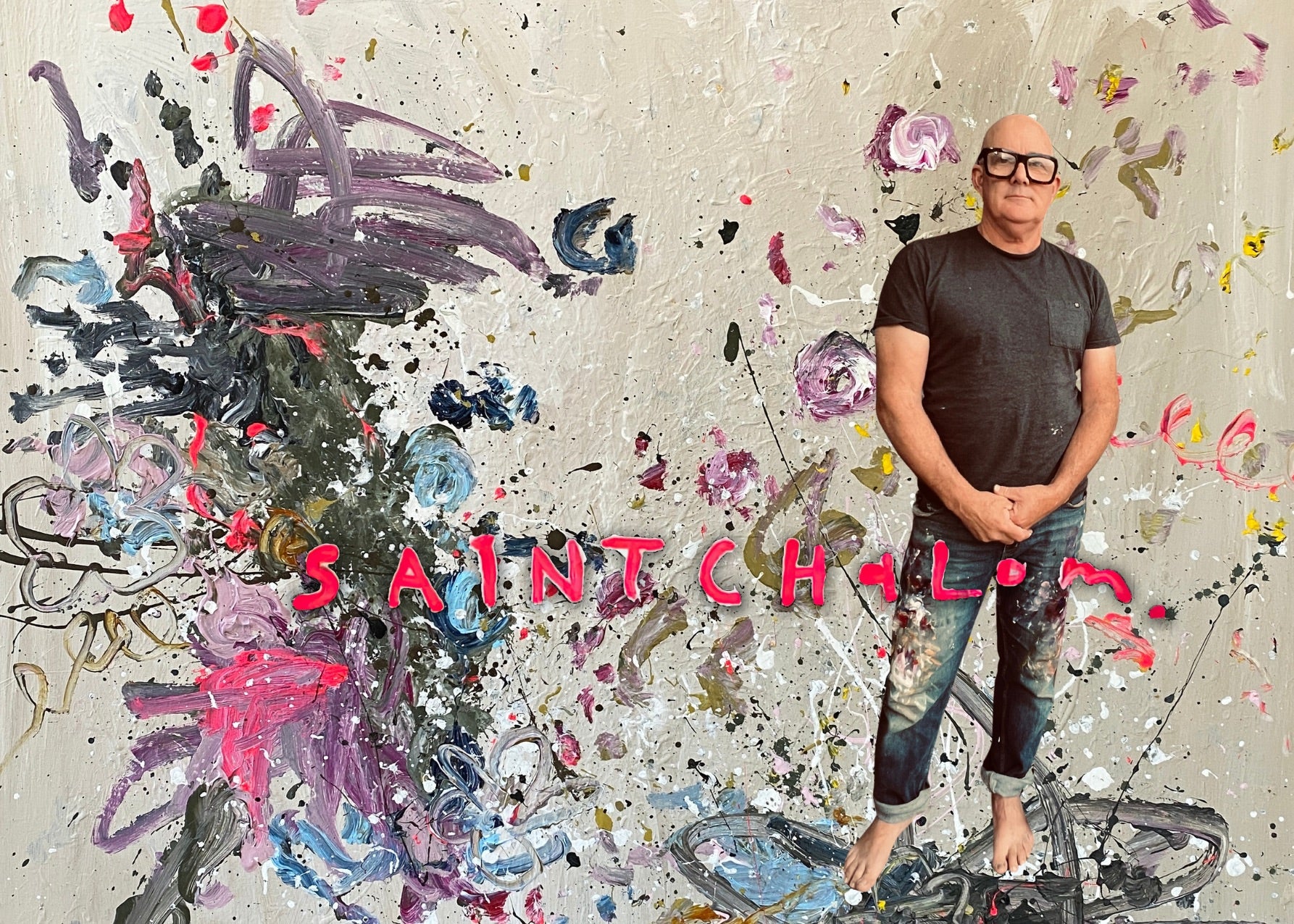 Person standing in front of a colorful abstract wall with 'Saint Chalom"' text.